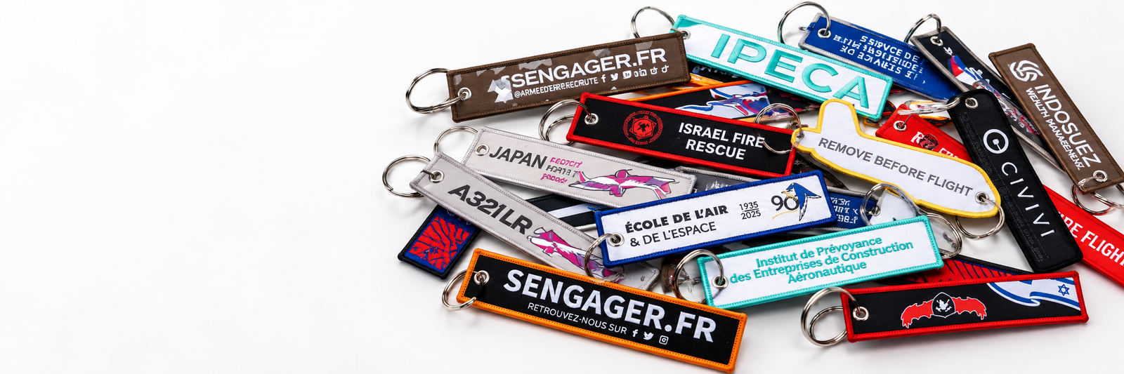 Embroidered key fobs with merrowed borders and metal rings, photographed on a dark plate.
