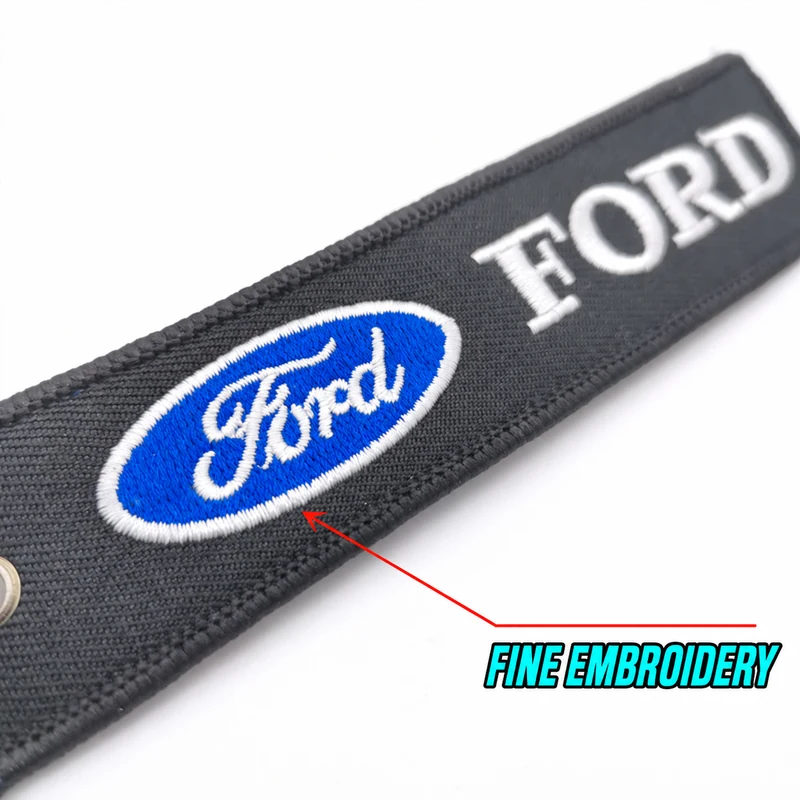 Close-up of a black Ford embroidered fabric keychain with a blue oval emblem and fine stitching callout.