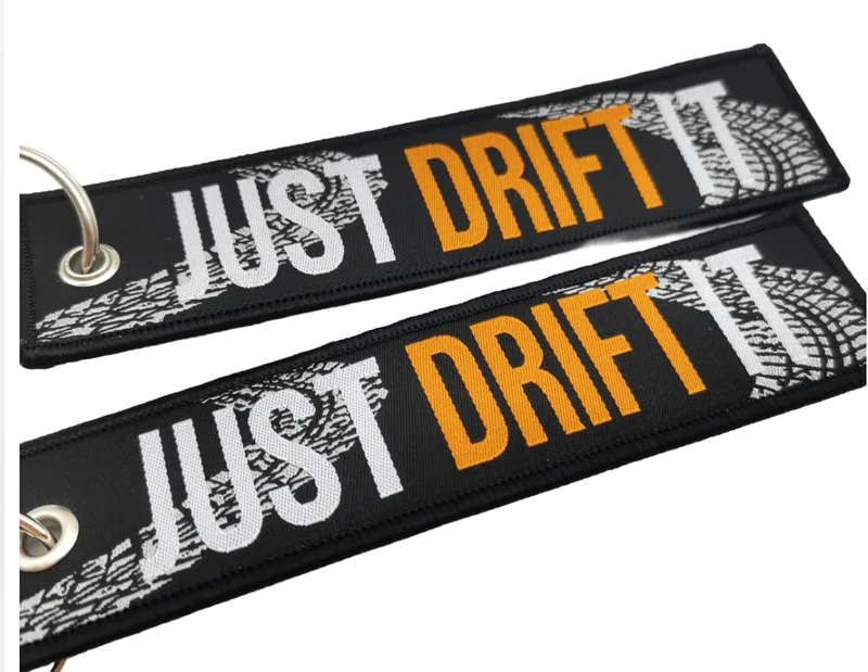 Two black Just Drift It embroidered fabric key tags with orange and white lettering.