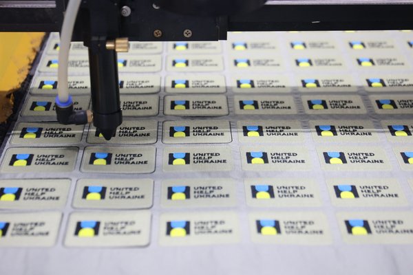 Vision laser cutter trimming the edge contour of custom patches on the LOVECOLOUR finishing line