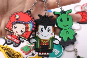Soft PVC character keychains including a red-hatted figure, dark haired figure and green motif.