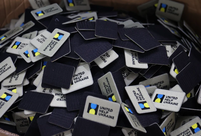 Assorted small dark fabric patches and labels piled on production table