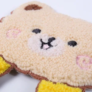 Close-up of a soft beige teddy bear chenille patch with embroidered facial details