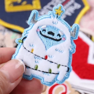 Blue and white smiling cartoon character patch with a yellow star held by hand