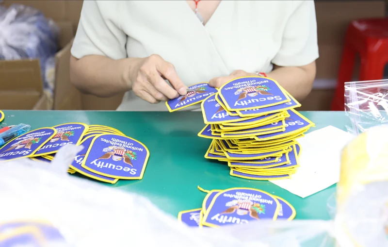 Worker sorting blue and yellow emblem patches into neat stacks