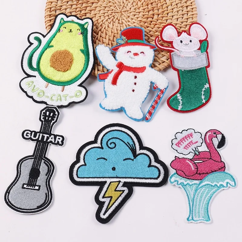 Avocado, snowman, stocking, guitar and cloud embroidered patches displayed on a woven mat