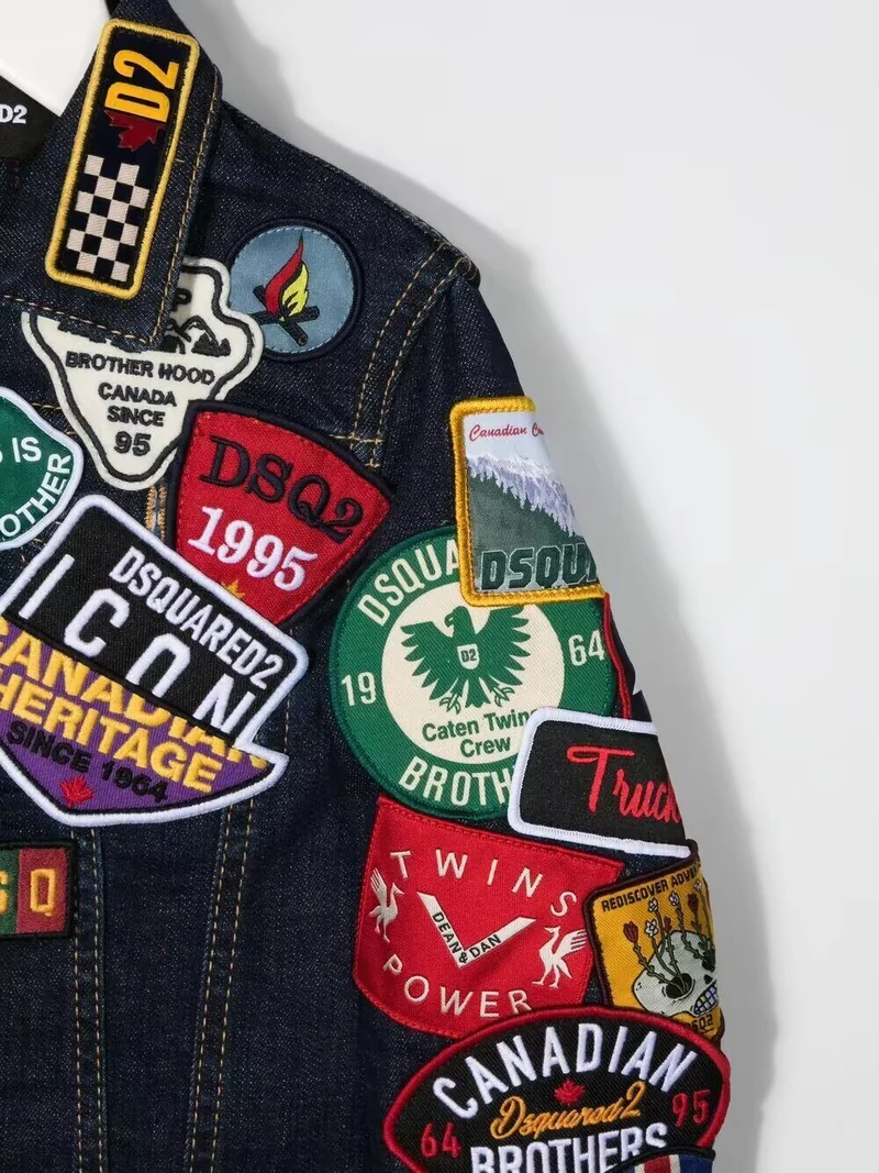 Black jacket sleeve decorated with colorful travel, text and illustrated patches.