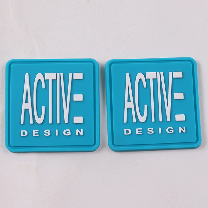 Pair of square blue PVC rubber labels with raised white Active Design logo
