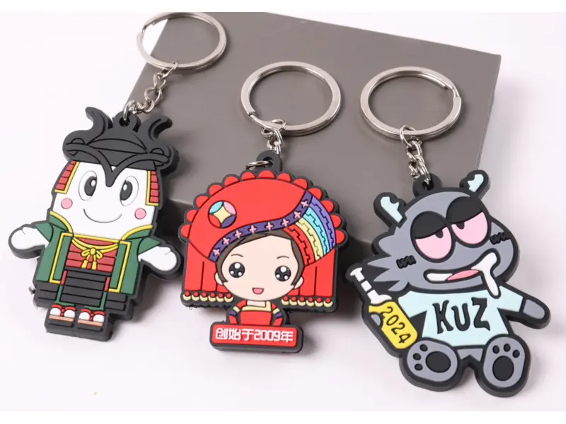 Three colorful custom PVC rubber character keychains with metal chains and split rings