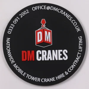 Black round DM Cranes PVC patch with red and white raised company logo