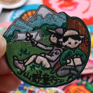Round embroidered patch with mountain landscape outdoor figure and green text