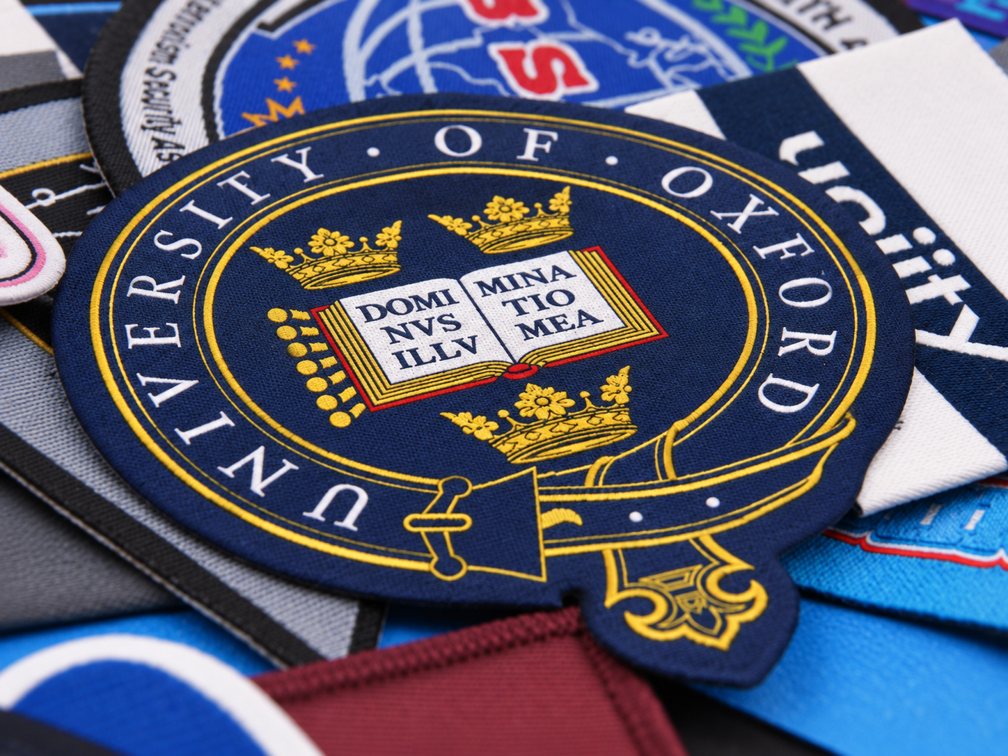 Close-up of a round custom woven university emblem patch with navy blue, gold and red details