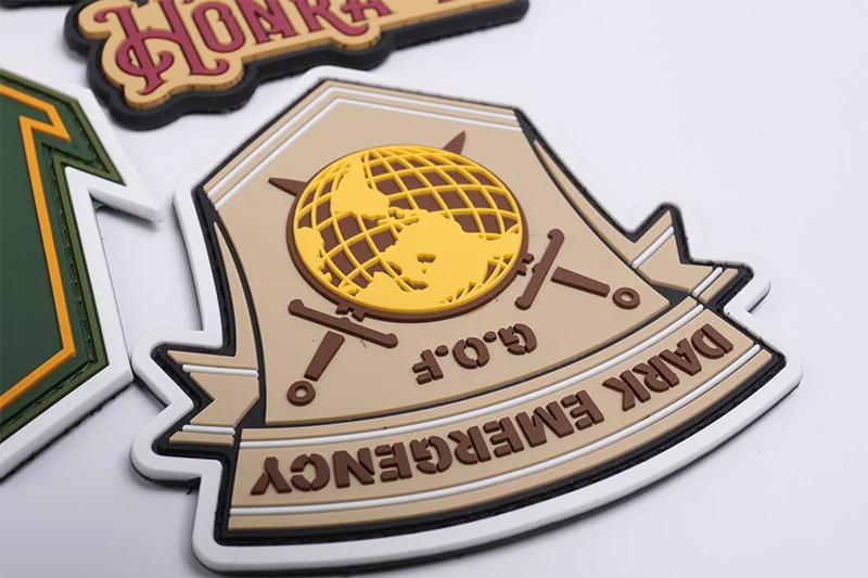 Close-up of a cream shield PVC patch with yellow emblem and dark lettering.
