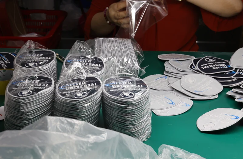 Stacks of round gray emblem patches with clear bags on packing table