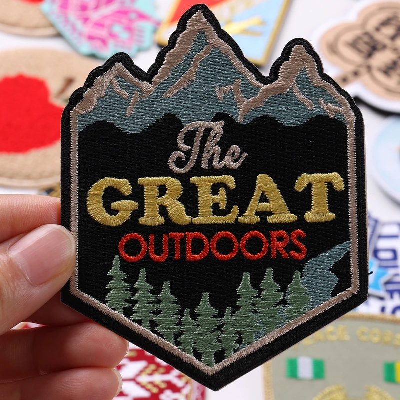 Shield-shaped Great Outdoors embroidered patch with mountains and pine trees