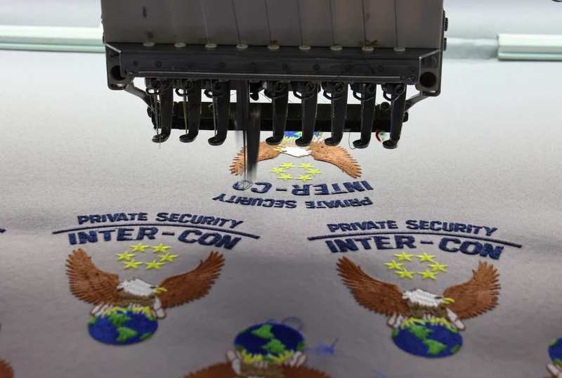 Embroidery machine over repeated Inter-Con eagle and globe emblems