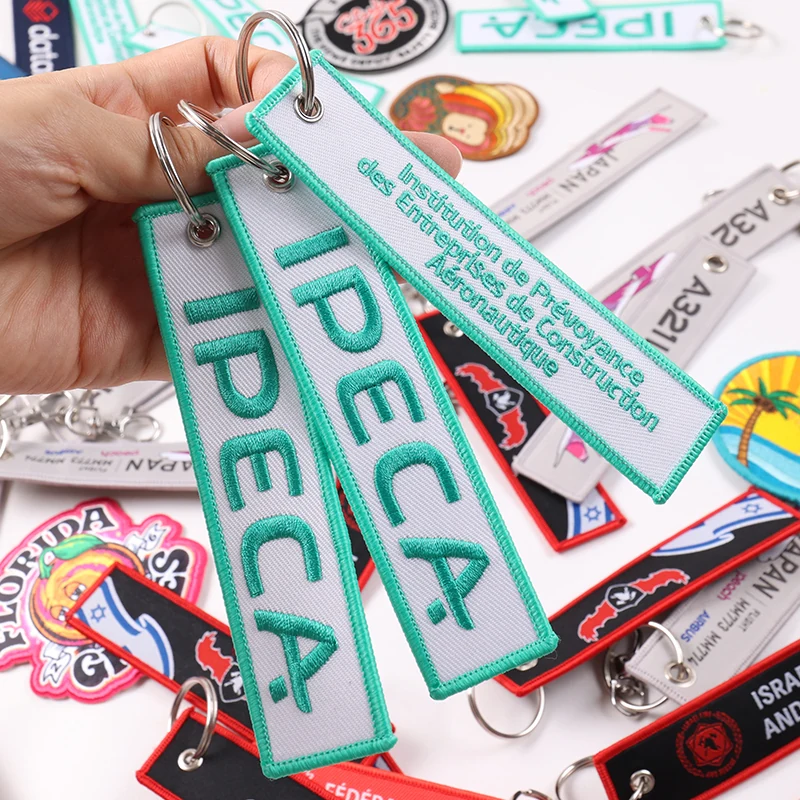 Three white fabric key tags with green IPECA lettering and metal rings