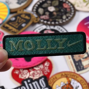 Rectangular dark green embroidered name patch reading Molly
