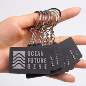 Hand holding multiple black Ocean Future Zone PVC keychains