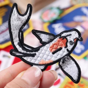 Black and white orca whale embroidered patch held by hand