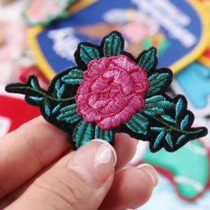 Pink embroidered rose with green leaves and dark stitched outline