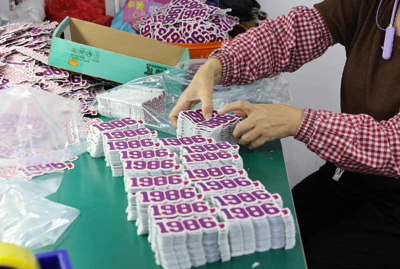 Worker organizing stacks of purple 1986 patch pieces for packing