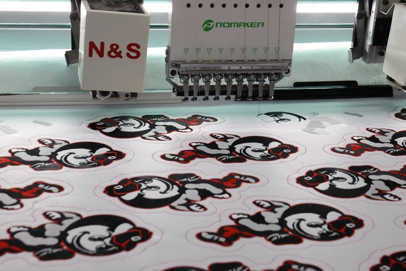 Embroidery heads above repeated red and black cartoon character designs