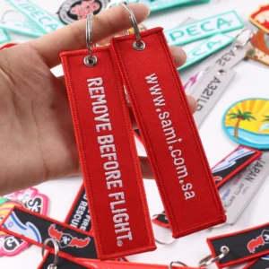 Two red fabric keychain tags including Remove Before Flight design