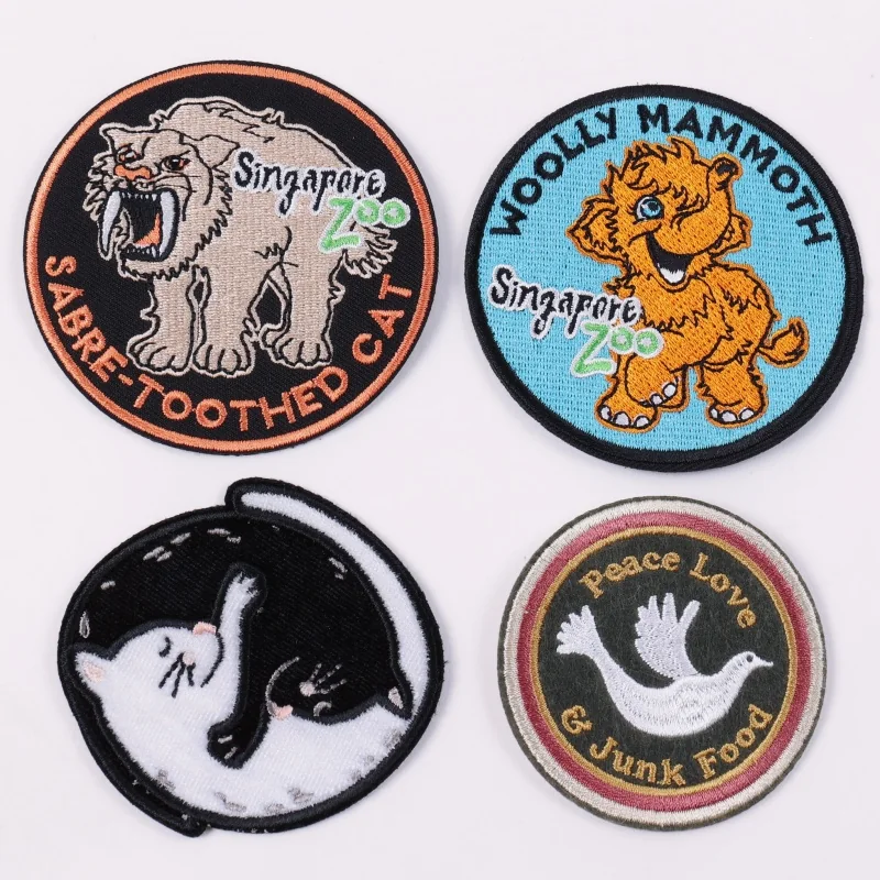 Four round animal themed embroidered patches featuring a mammoth, panther and birds
