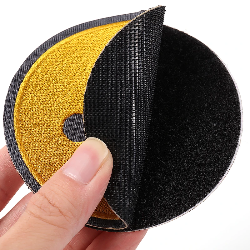 Round yellow smiley chenille patch showing black hook and loop backing