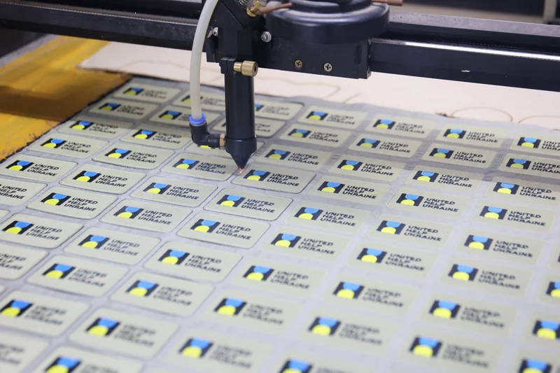 Machine head above sheet of repeated small rectangular printed patch labels
