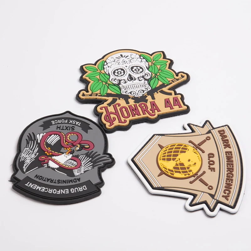 Three custom PVC rubber patches showing a skull, a bird emblem and an emergency shield.