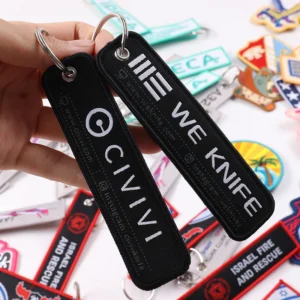 Two black fabric key tags with large white lettering and silver metal rings