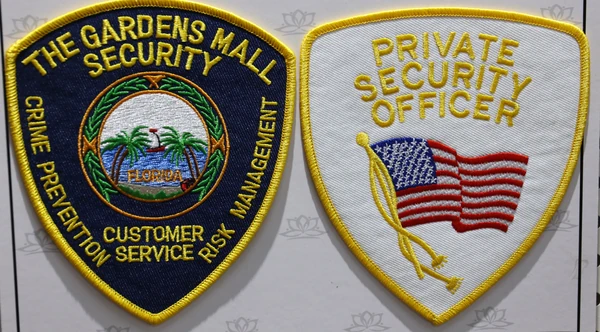 Black oval THE GARDENS MALL SECURITY patch beside a white PRIVATE SECURITY OFFICER shield patch with an American flag and yellow border.